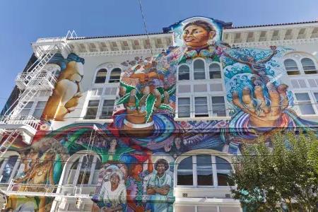 A colorful, 贝博体彩app教会区妇女建筑侧面的大型壁画.